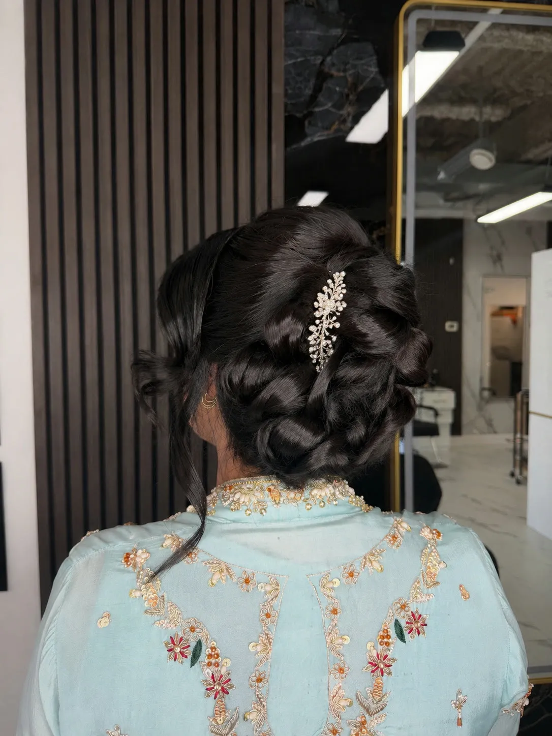 Low braided updo with a jeweled hairpin by Ronak Hairstylist in Toronto