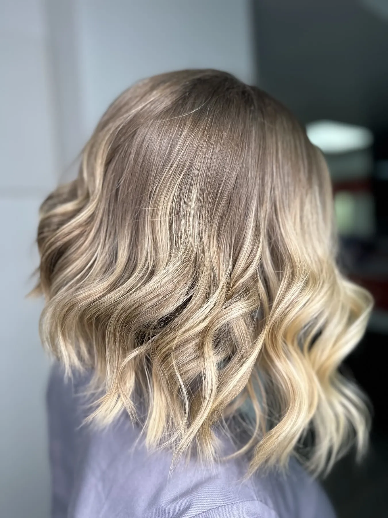 Soft beige blonde balayage on a wavy lob by Ronak Hairstylist in Toronto